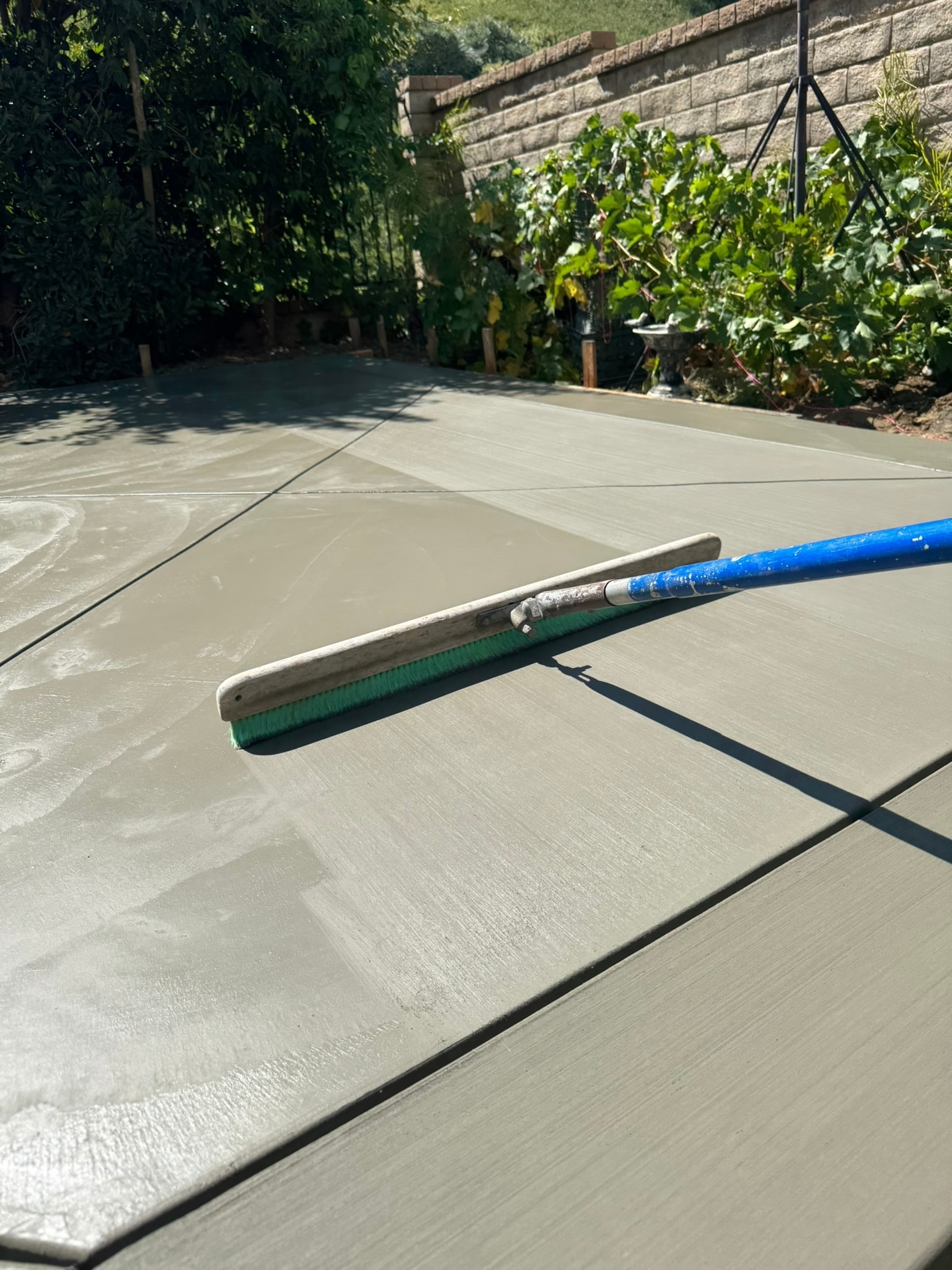 Concrete contractor broom-finishing a freshly poured patio in Los Angeles County — Concrete Etc., Inc.