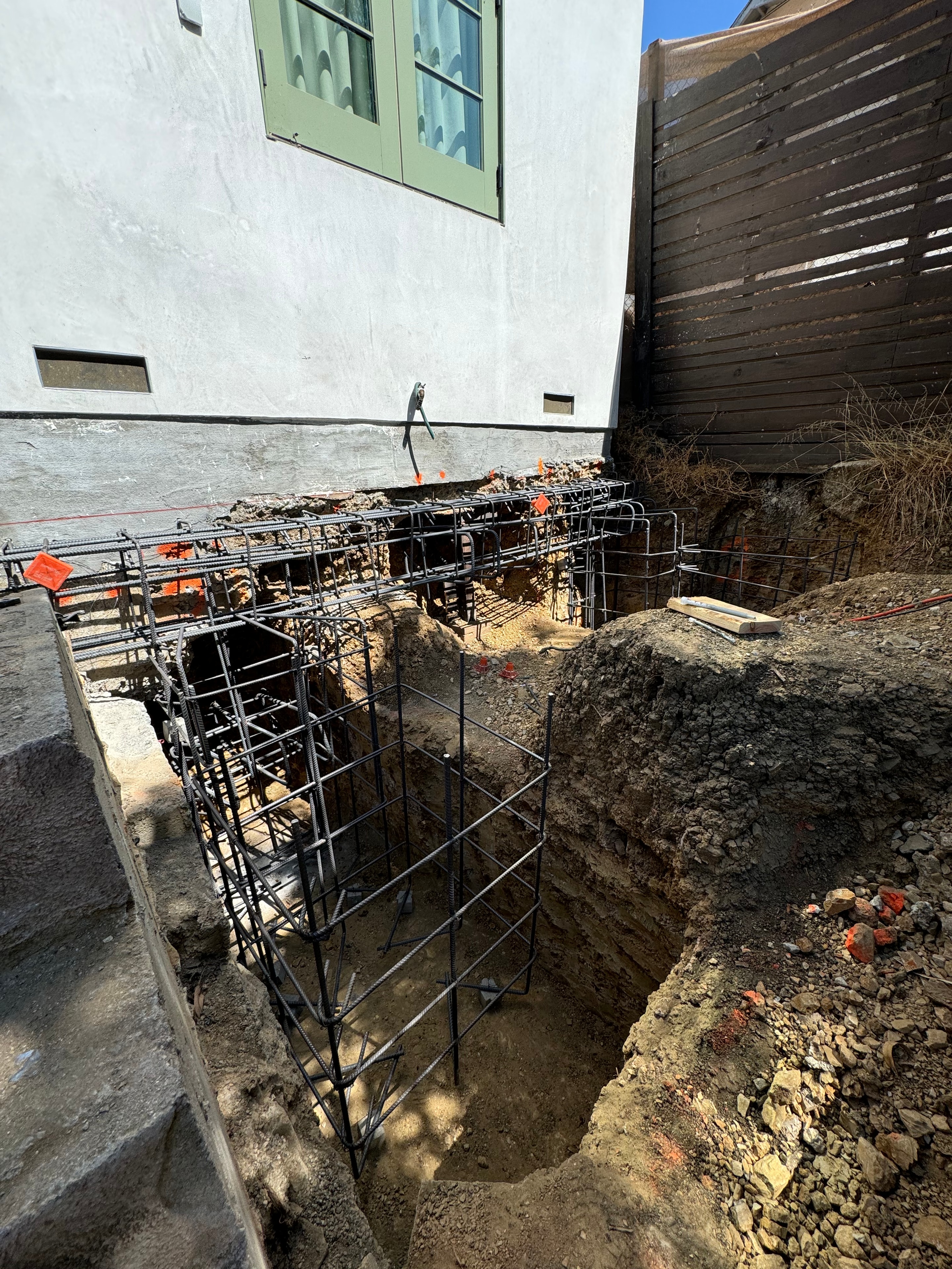Concrete foundation underpinning excavation with heavy rebar cage alongside existing building in Los Angeles, CA by Concrete Etc., Inc.