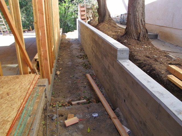 Poured-in-place concrete retaining wall under construction adjacent to new home framing in Brentwood — Concrete Etc., Inc.