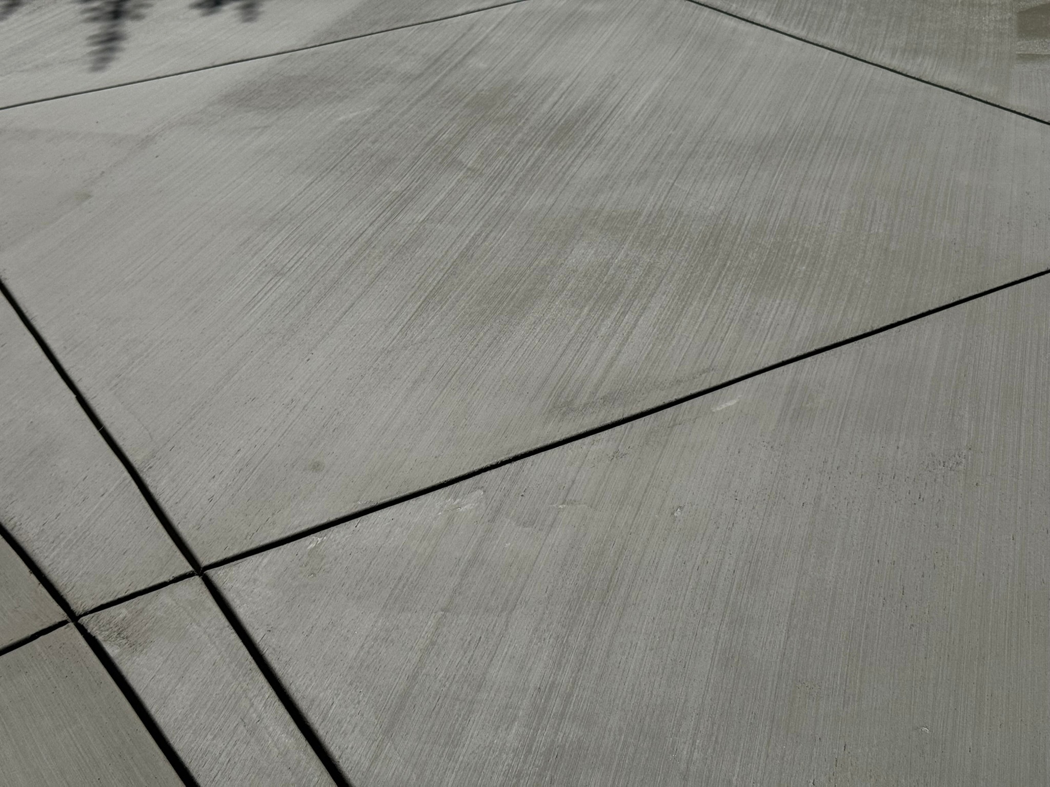 Close-up of broom finish concrete patio surface with decorative score lines in Santa Clarita, CA by Concrete Etc., Inc.