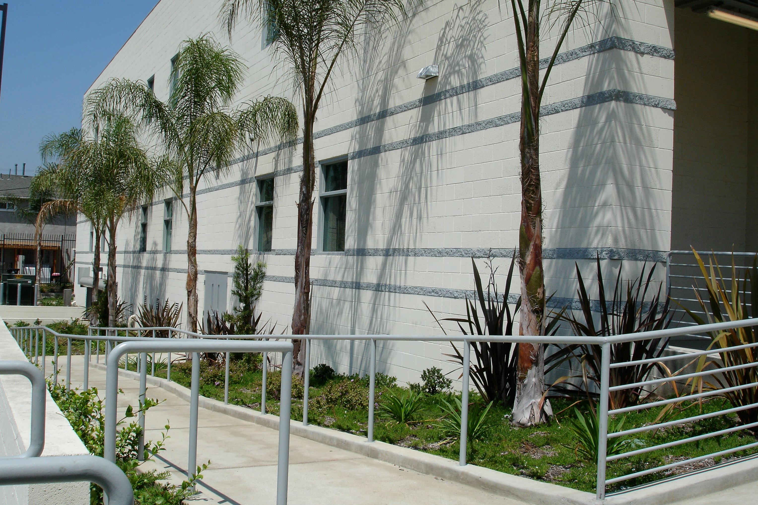 Completed ground-up commercial Social Security building with white CMU block walls, blue accent bands, ADA ramp, concrete walkways and landscaping in Los Angeles by Concrete Etc., Inc.
