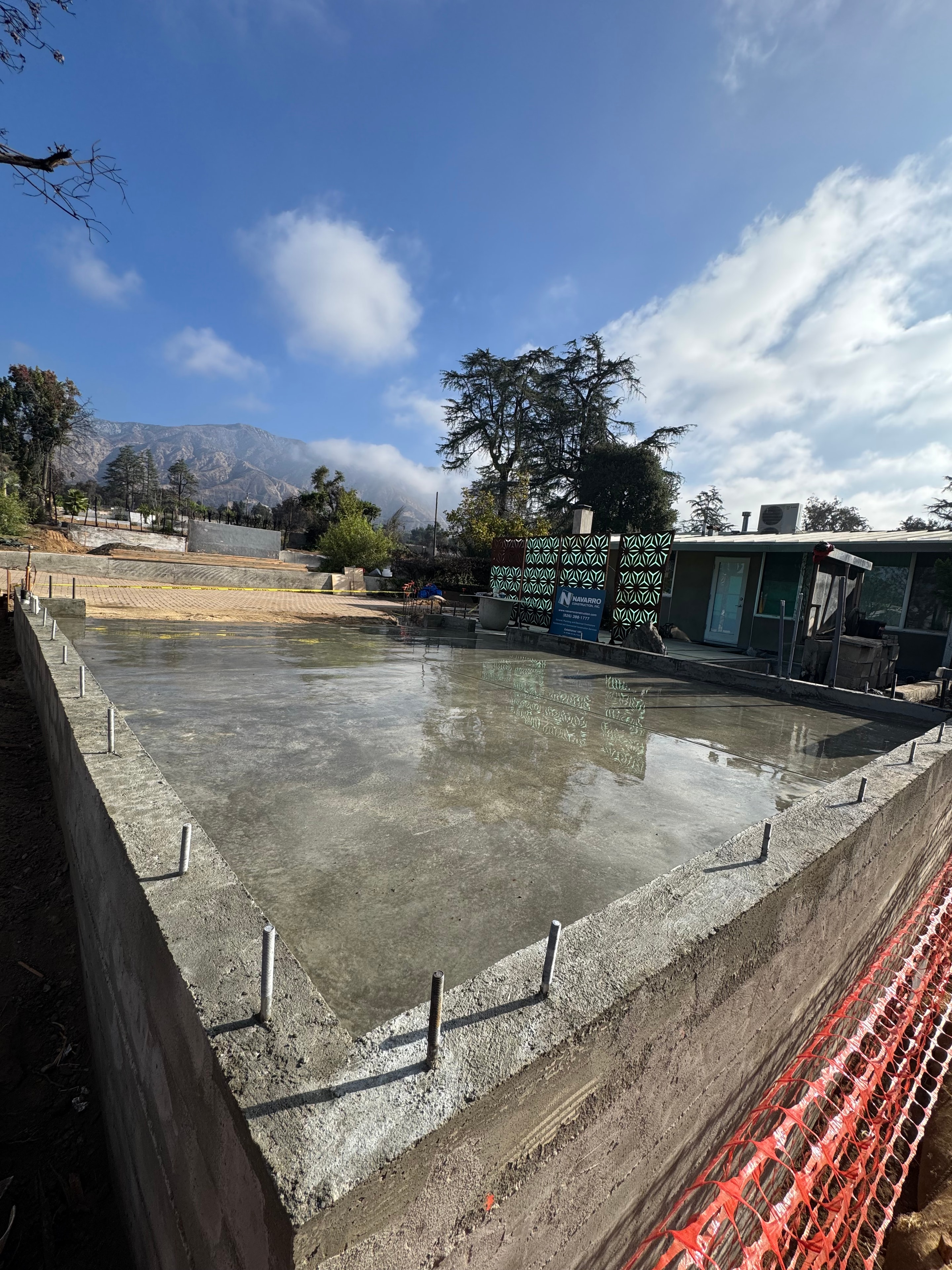 Freshly poured structural concrete slab foundation with anchor bolts and gravel base under construction in Altadena, CA by Concrete Etc., Inc.
