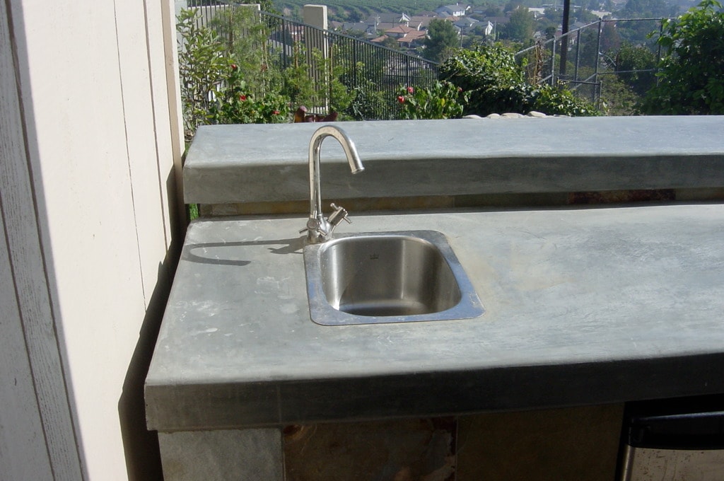 Custom concrete countertop with stainless steel sink on outdoor kitchen overlooking hillside neighborhood in Los Angeles by Concrete Etc., Inc.