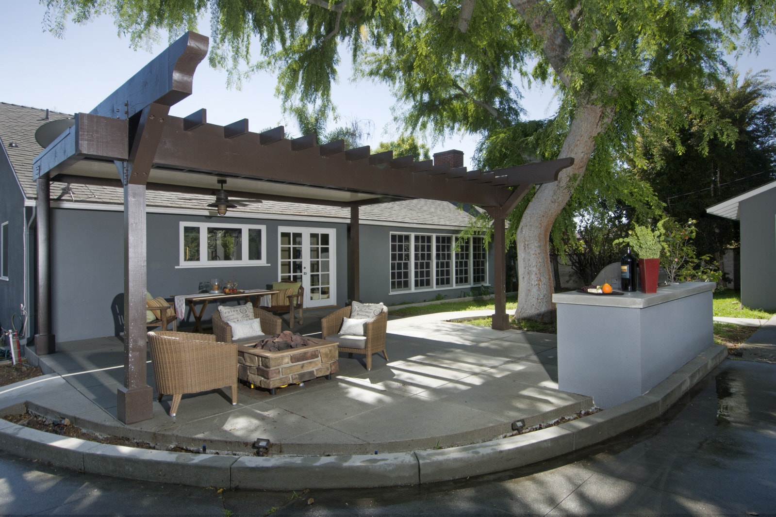 Modern outdoor living space with pergola, concrete patio, seating area and outdoor kitchen island in Los Angeles by Concrete Etc., Inc.