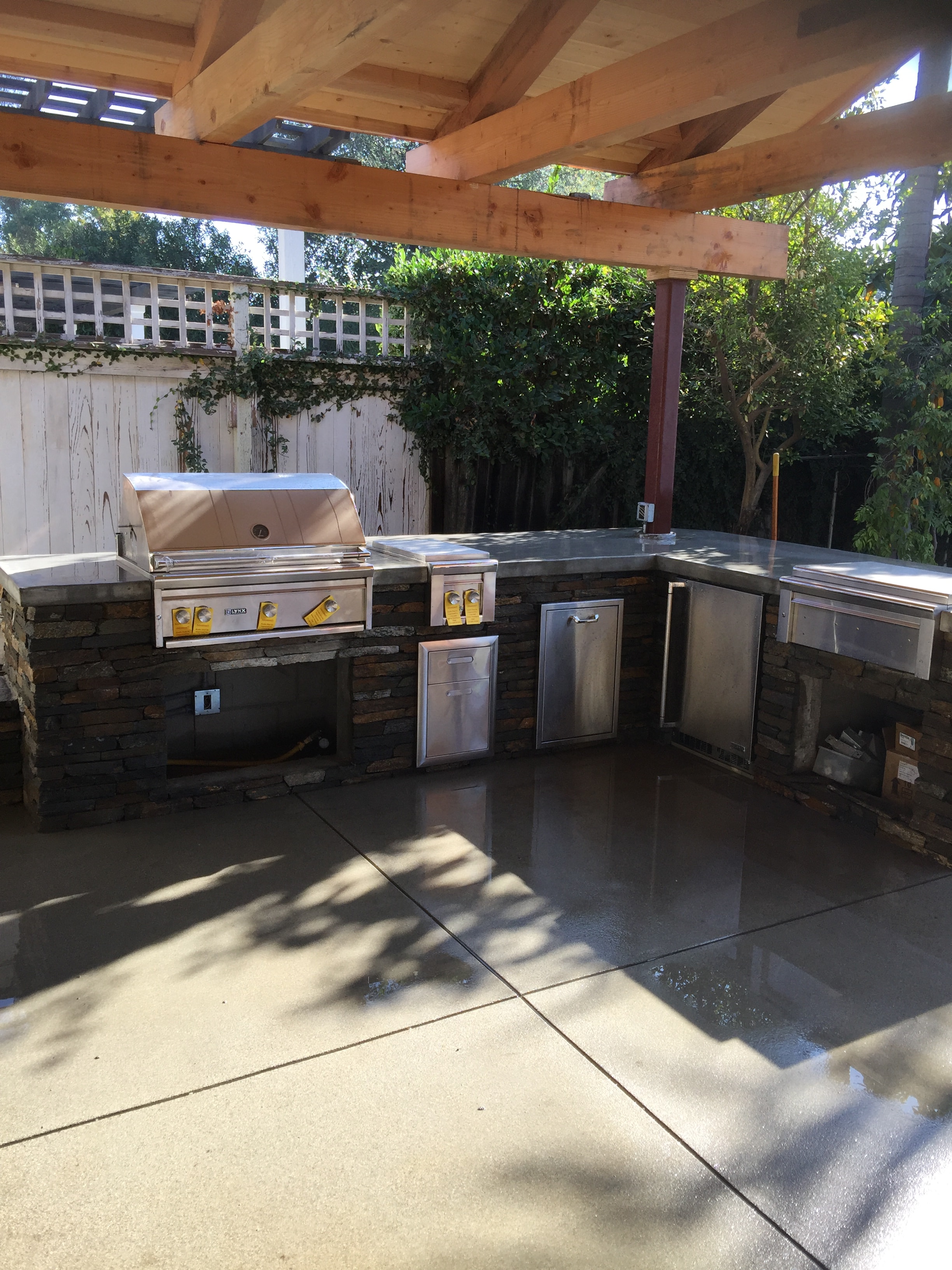 Outdoor kitchen with sand finish concrete patio, poured-in-place countertop, and natural stone veneer in Pasadena, CA