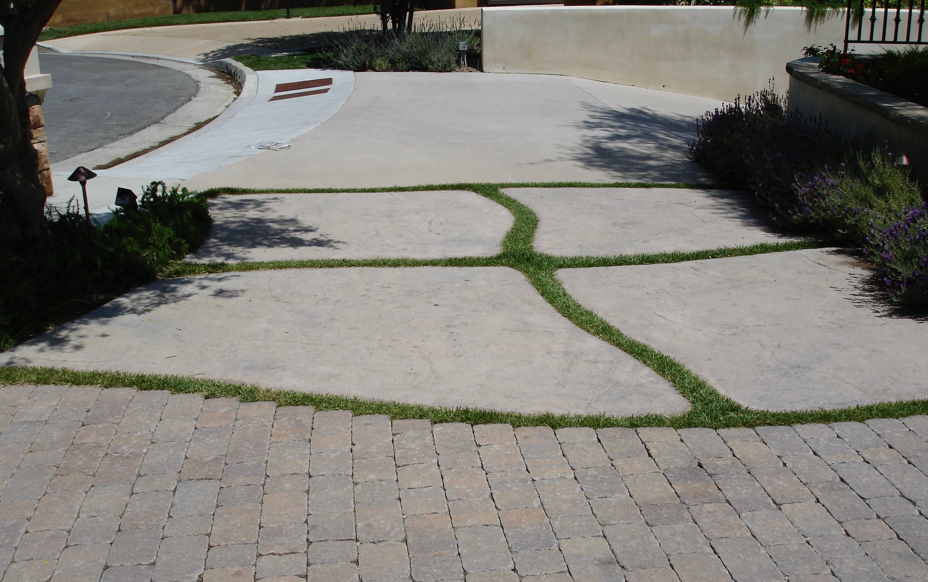 Hybrid driveway combining stamped concrete with grass joints and paver border installed by Concrete Etc., Inc.