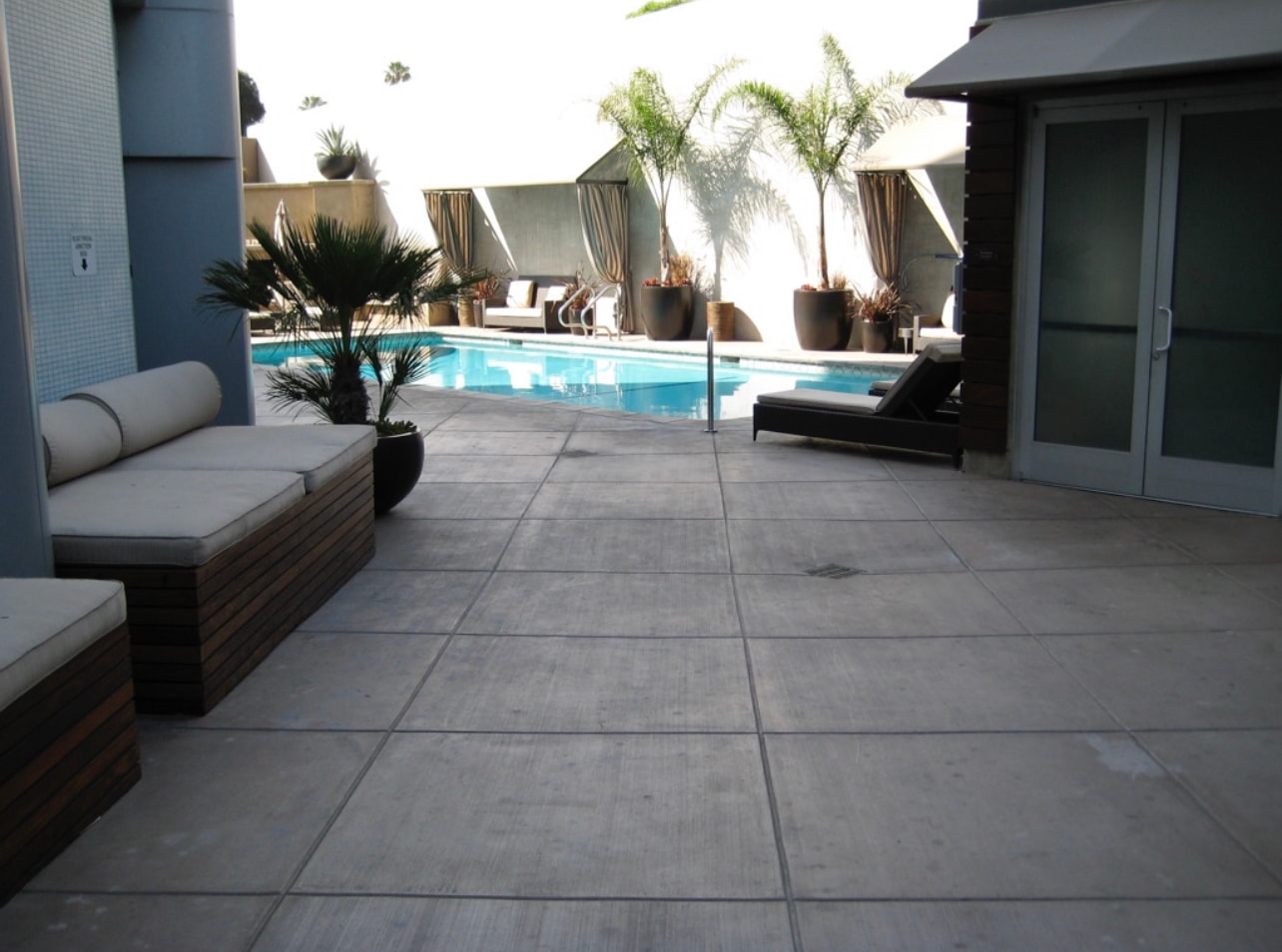 Broom finish concrete pool deck with diamond pattern control joints, outdoor fireplace and built-in benches at Hotel Angeleno in Los Angeles, CA by Concrete Etc., Inc.