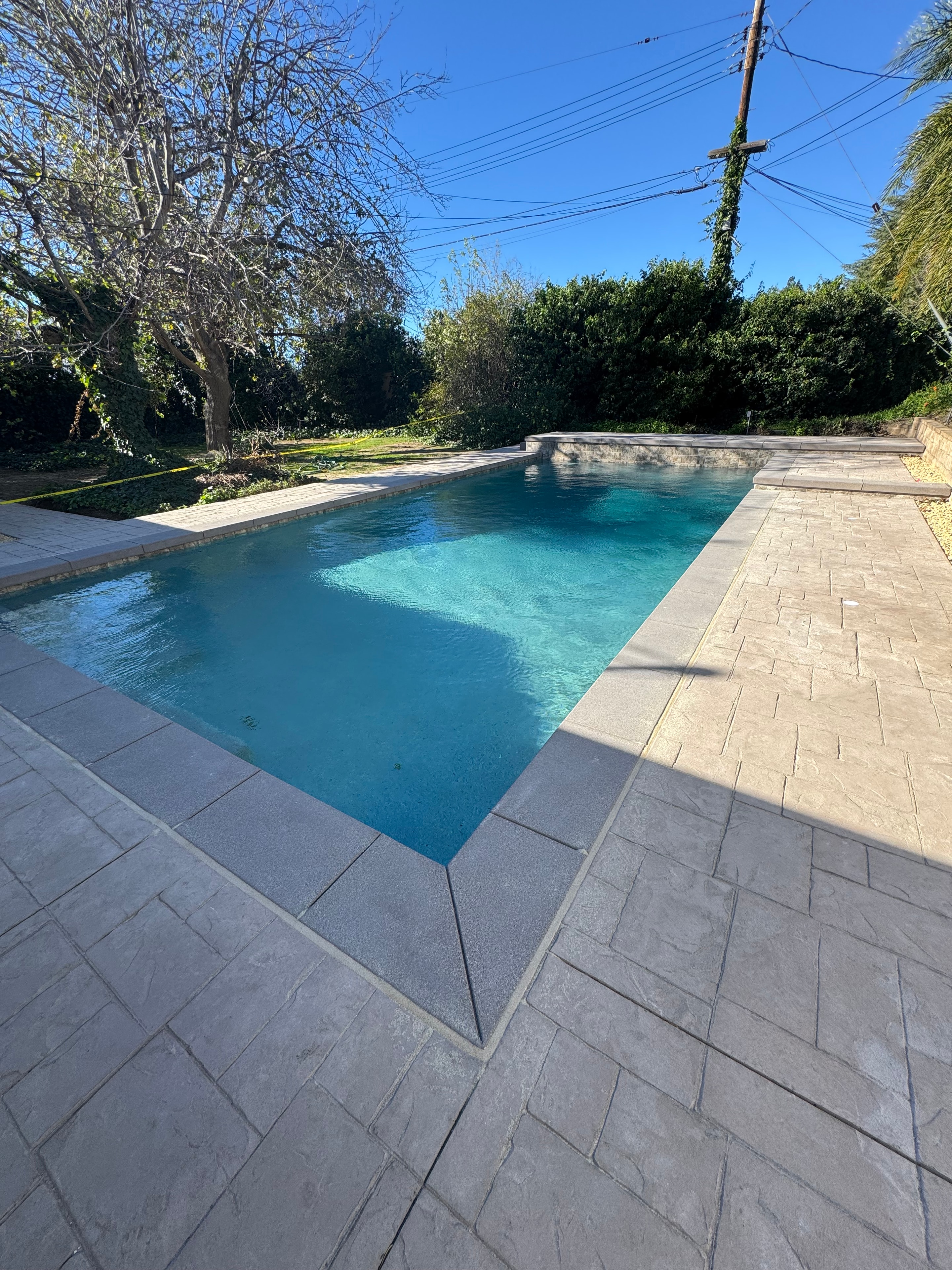 Stamped concrete pool deck with sand finish and coping in San Fernando Valley by Concrete Etc., Inc.