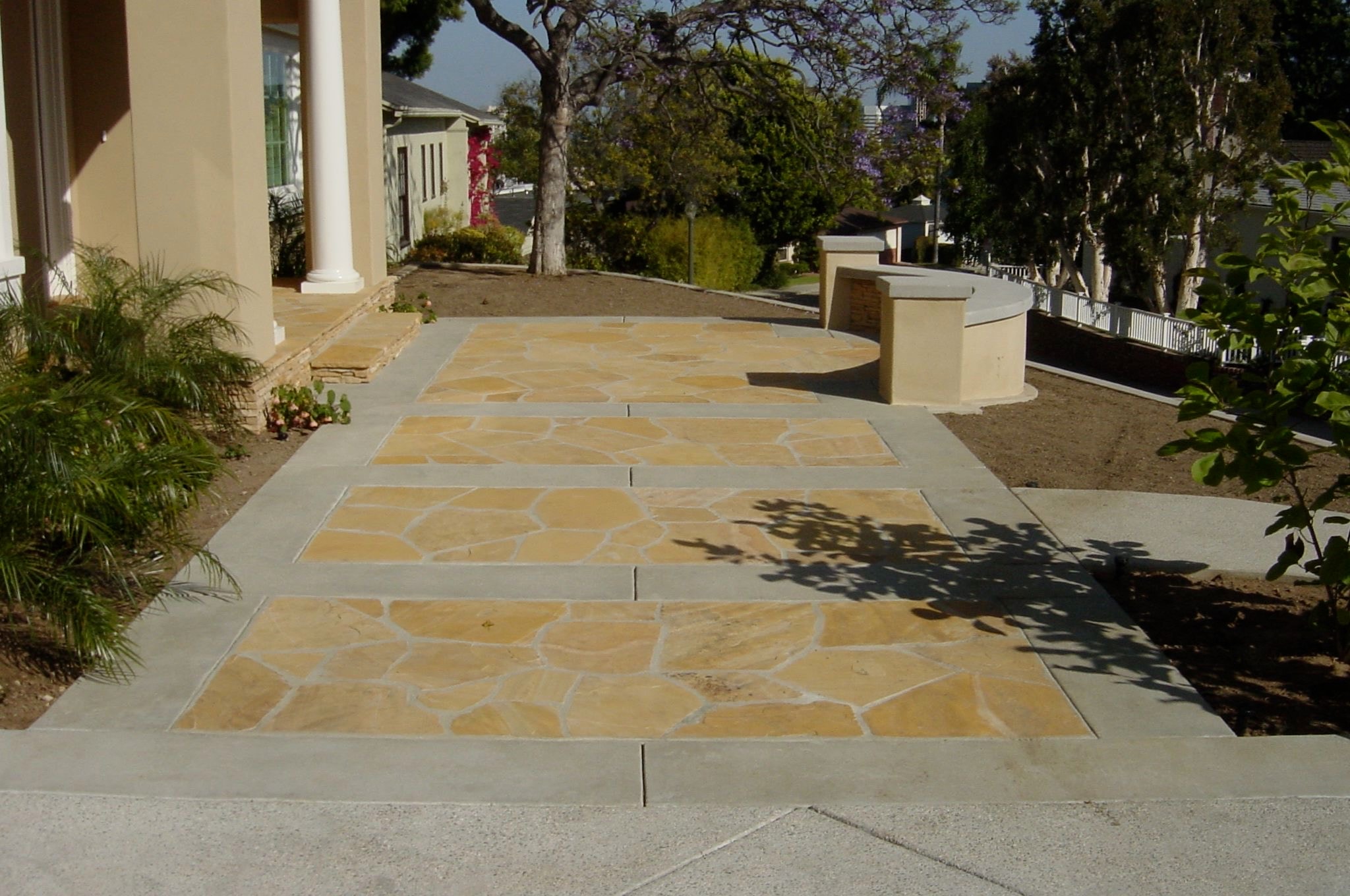 Sand finish concrete driveway with smooth borders and decorative flagstone inlays installed in Los Angeles, CA by Concrete Etc., Inc.