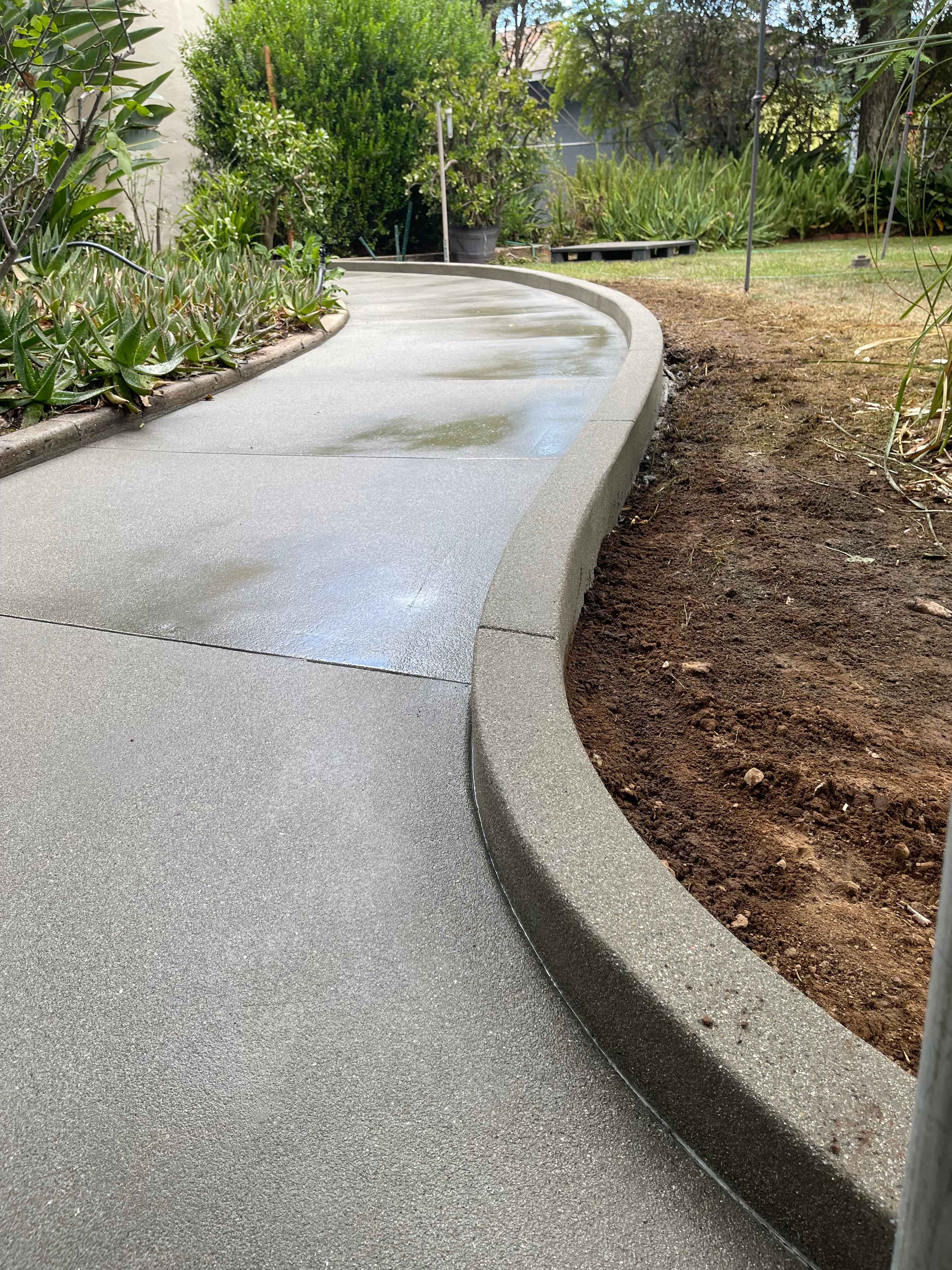Sand finish concrete walkway with river rock borders and steel edging at modern home in Pasadena, Los Angeles County by Concrete Etc., Inc.