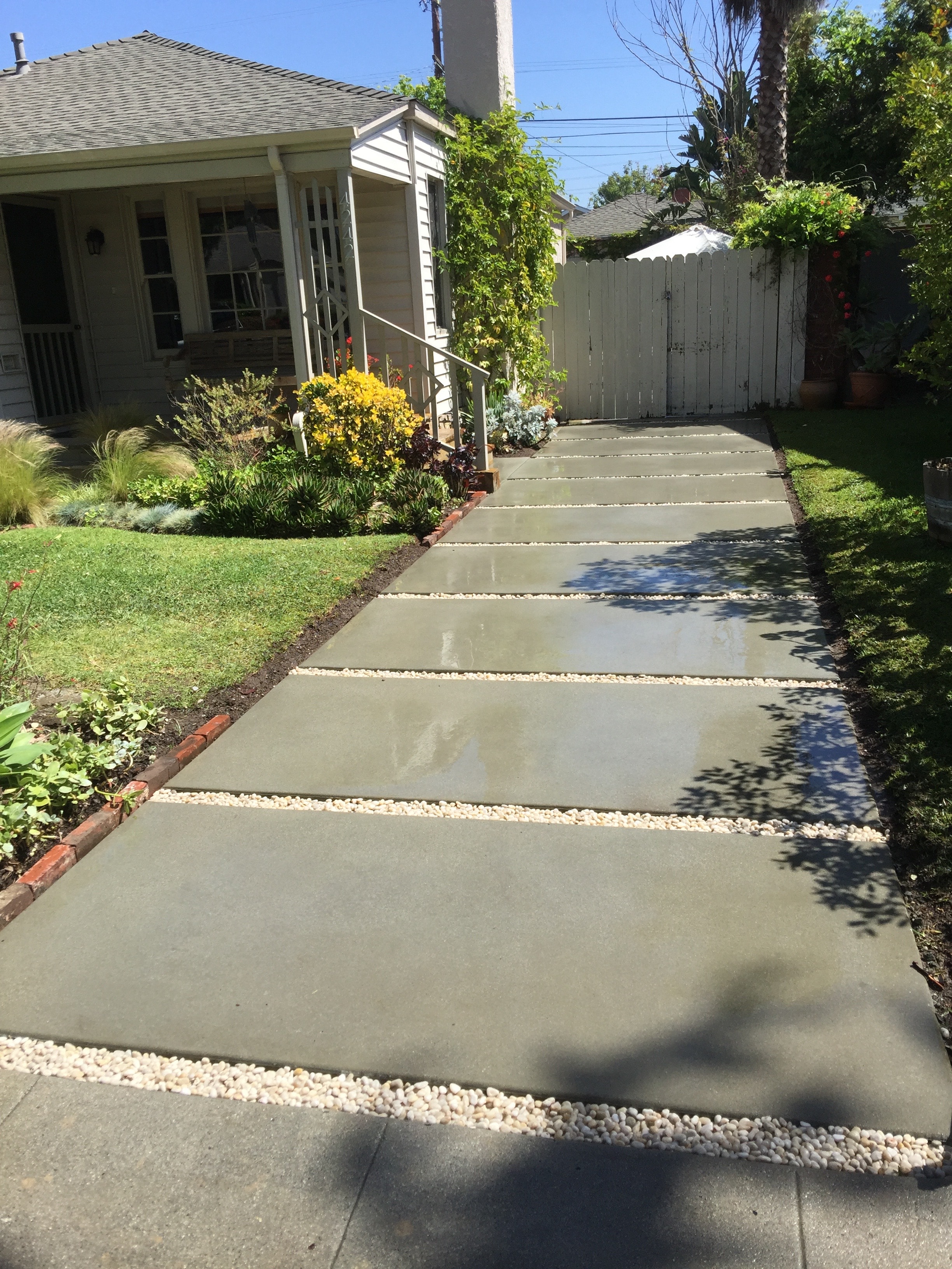 Sand finish concrete driveway with decorative river rock gravel strips at residential home in Culver City, Los Angeles by Concrete Etc., Inc.